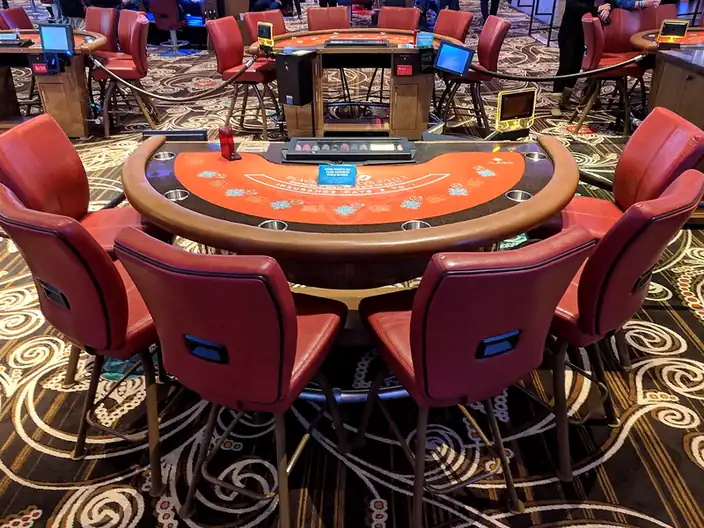 Üres blackjack-asztal bordó bőrszékekkel egy kaszinó játéktermében