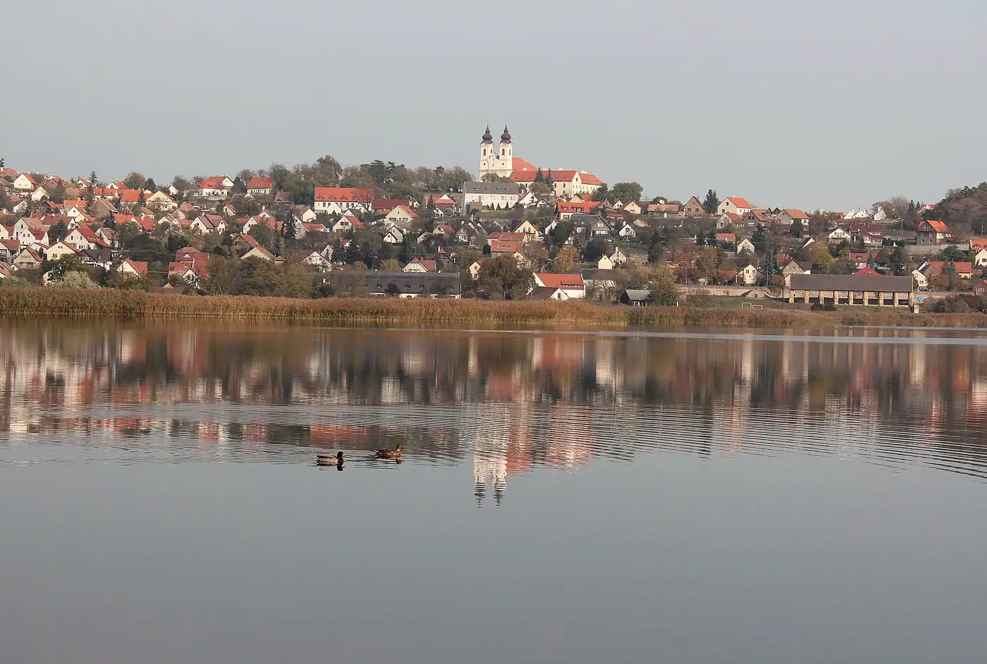A tihanyi Belső-tó csendes vize novemberben, fölötte a falu és az apátság két tornya